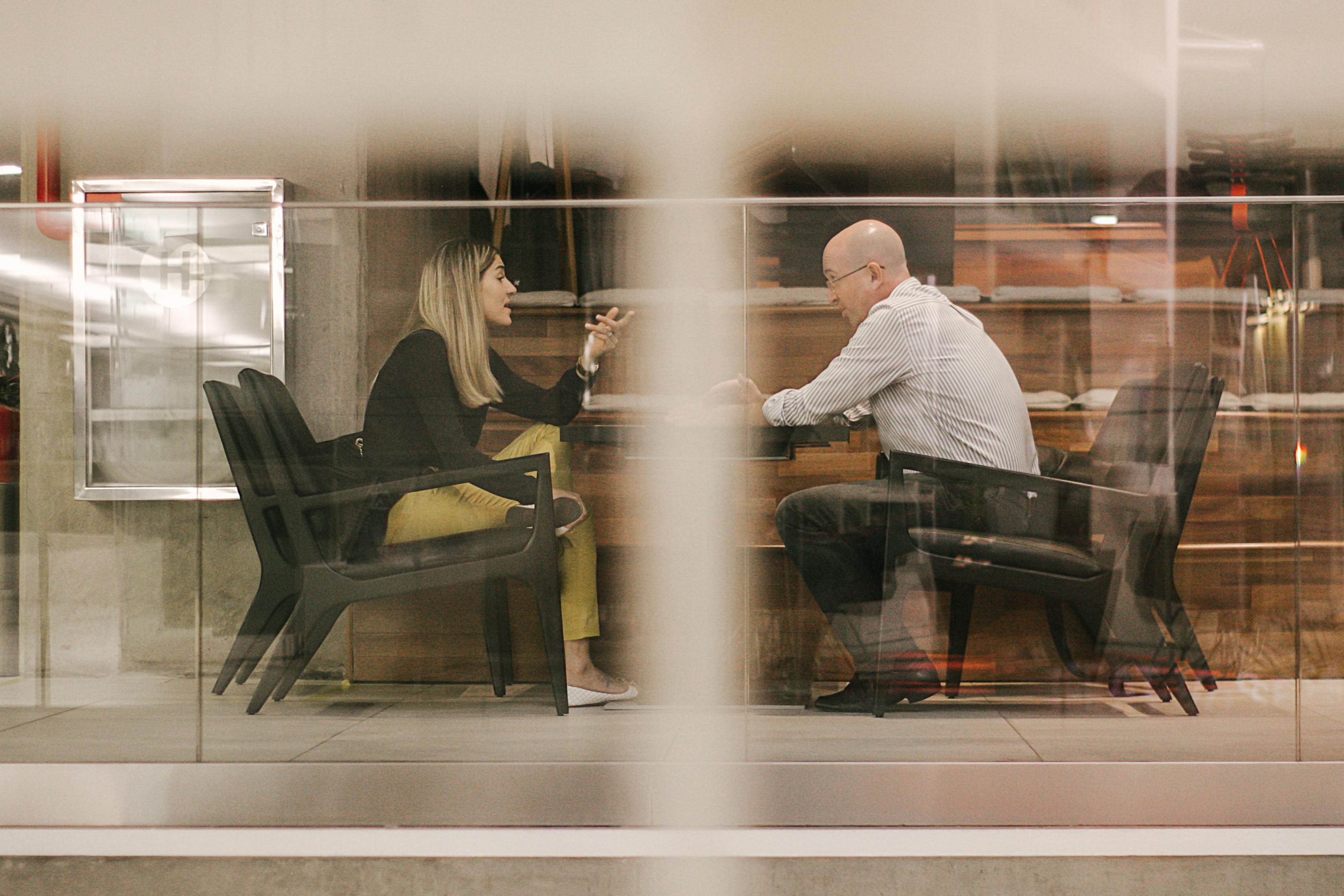 man-and-woman-sitting-on-black-wooden-chairs